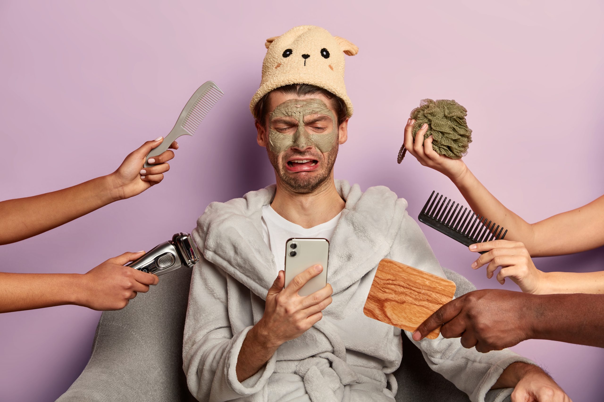Upset Caucasian male with clay mask on complexion, dissatisfied with result after beauty treatments, looks sadly at modern gadget, cannot find necessary information, gets grooming procedures